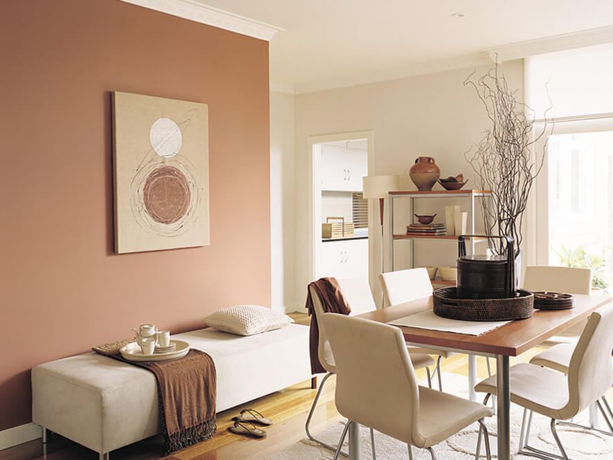 Neutral dining space with timber table and cream chairs and brown blanket on cushion bench plant